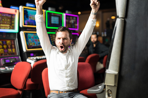 Portrait of an attractive Hispanic man looking very excited about winning some money playing slots in a casino