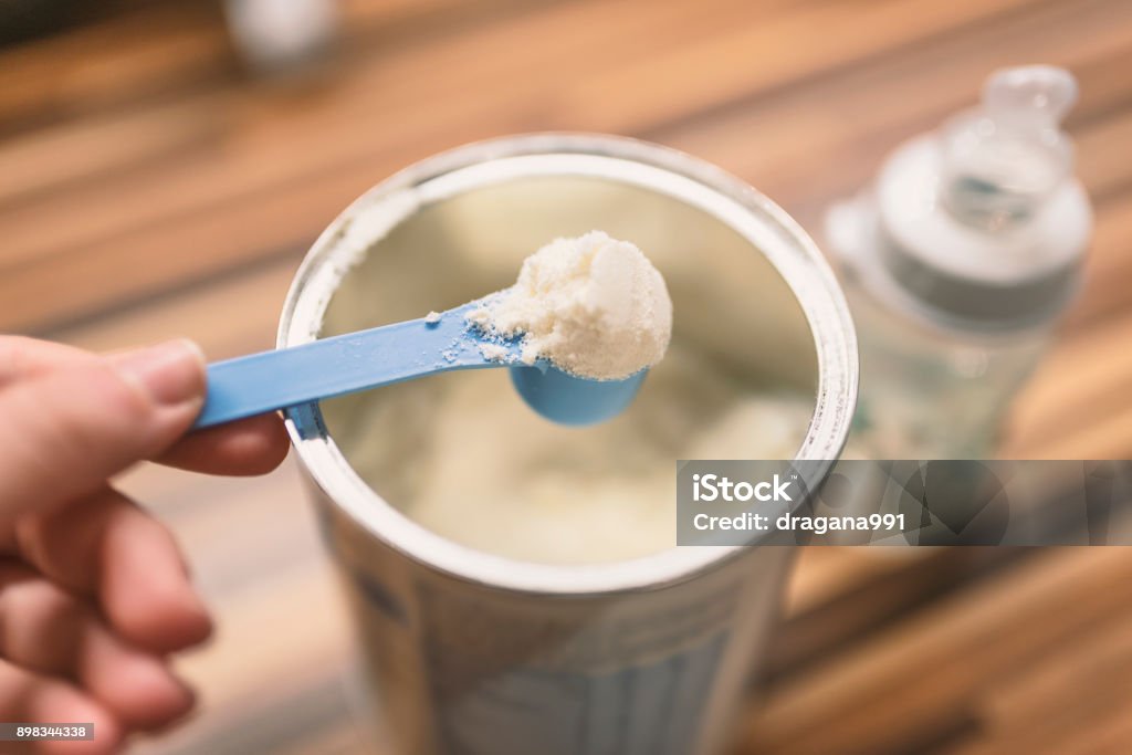 Baby Milk Formula and Baby Bottles Powder milk for baby and blue spoon on light background close-up. Milk powder for baby in measuring spoon on can. Powdered milk with spoon for baby. Baby Milk Formula and Baby Bottles. Baby milk formula on kitchen background Infant Formula Stock Photo