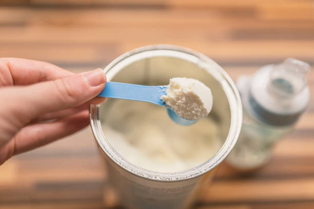 istock Powder milk for baby and blue spoon on light background close-up 898344346