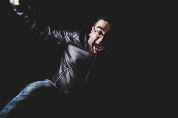 Portrait of a cheerful young man wearing black leather jacket, smiling and looking up, isolated on a blue background
