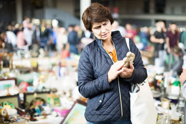 european female is visiting the market of old things and shopping outdoors.