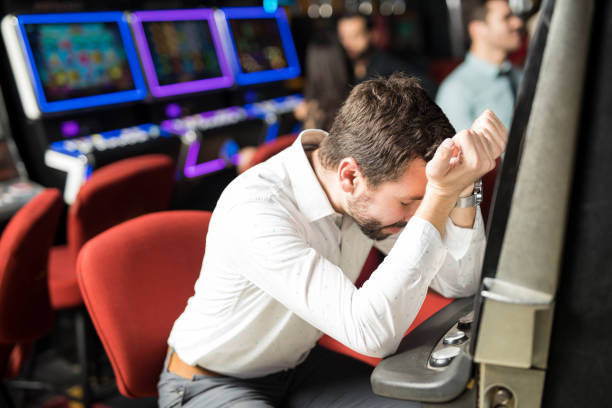 Unlucky young man feeling sad and stressed after losing his money playing slots in a casino