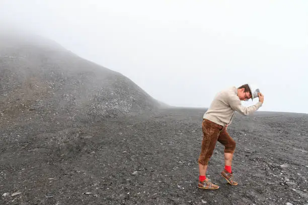 Mentally challenged individual in traditional clothing dances on a moonlike landscape in the mountains of the Swiss alps near Grimentz, Switzerland, on a cloudy day in summer