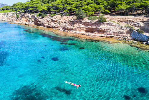 Girl snorkeling in the turquoise waters of Moni Island, next to Aegina Island in Greece