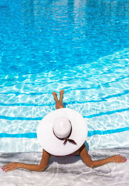 istock Elegant woman with white hat enjoys the pool 898364036
