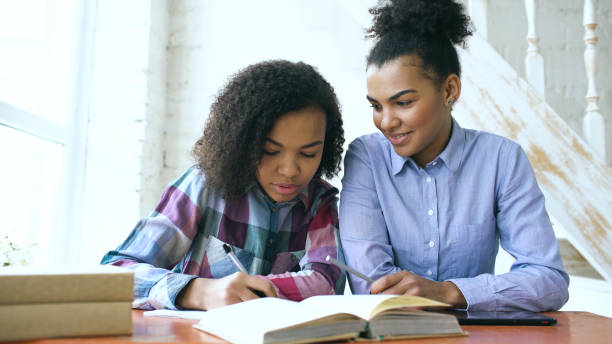 istock Mixed-race woman sits at the table with her sister while she studies 898374384