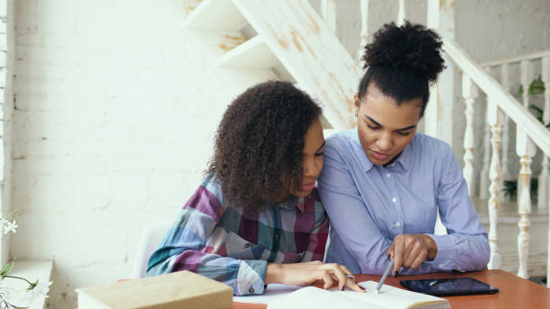 istock Mixed-race woman sits at the table with her sister while she studies 898374404