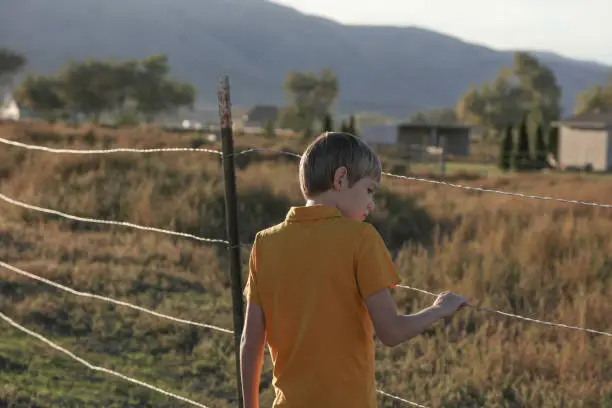 Boy holding barbed wire fence