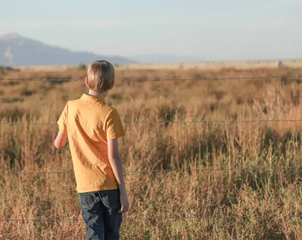 Boy holding barbed wire fence