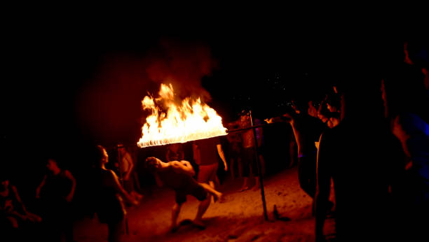 Koh Tao, Thailand - December 10, 2017: Young people partying and dancing limbo at fire show on the beach