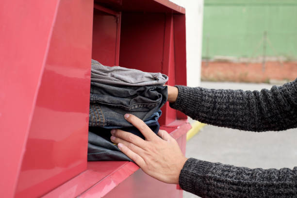 istock man depositing used clothes in a clothing bin 898378040