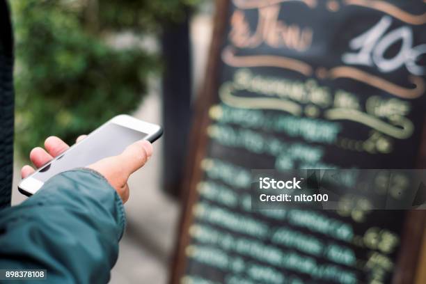 Hombre Usando Un Smartphone Frente A Un Restaurante Foto de stock y más banco de imágenes de Restaurante