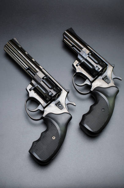 istock two shiny black revolvers on a black background. 898380376