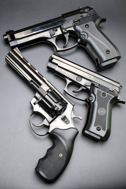 istock three shiny black pistols on a black background. 898380390
