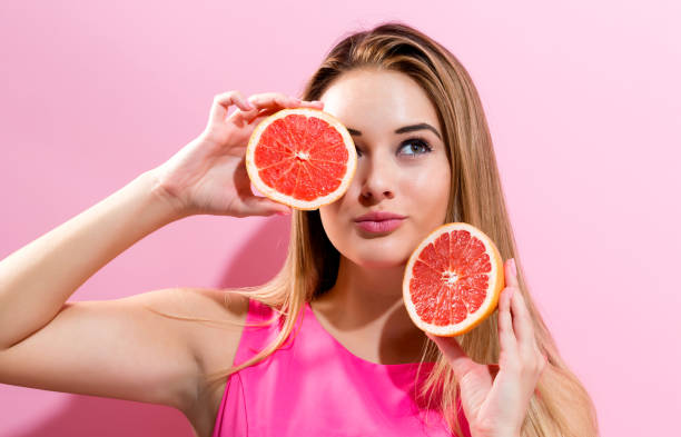 istock Happy young woman holding grapefruit halves 898380756