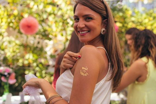 Maid of honor at bachelorette party with glitter tattoo on her arm