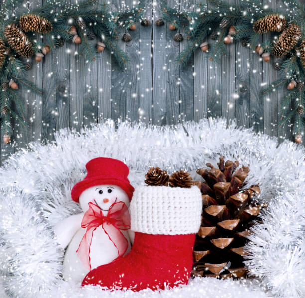 istock Christmas composition with smiling snowman, Santa's boot and pinecone on wooden boards background 898389118
