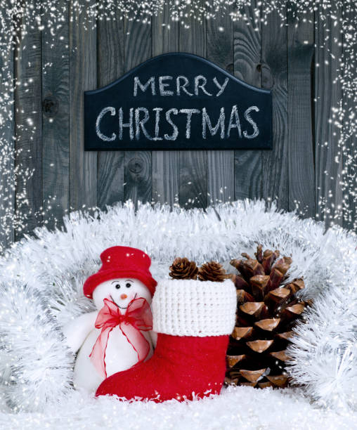 istock Christmas composition with smiling snowman, Santa's boot and pinecone on wooden boards background 898389140