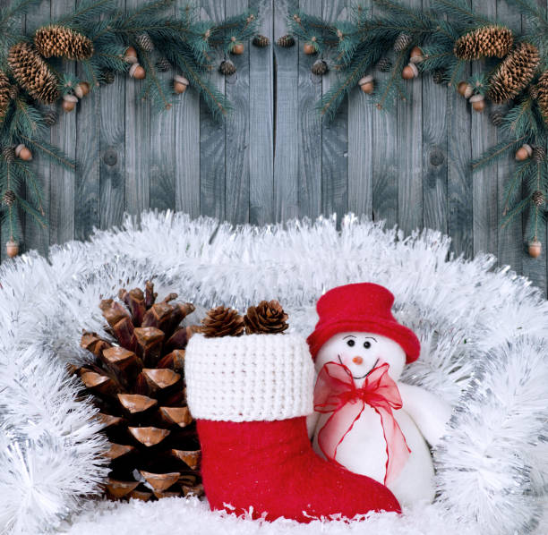istock Christmas composition with smiling snowman, Santa's boot and pinecone on wooden boards background 898389180