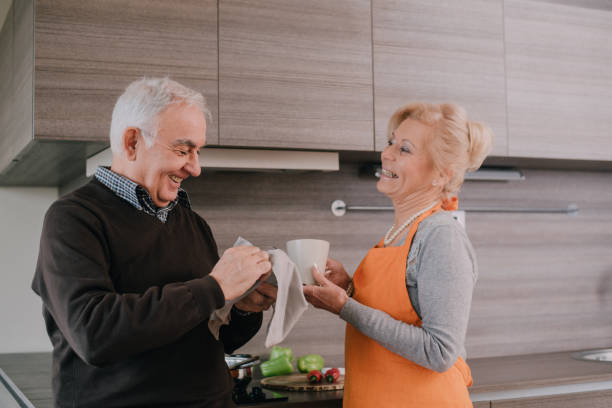 istock Happy senior couple laughing in a kitchen while wiping the dishes 898395026