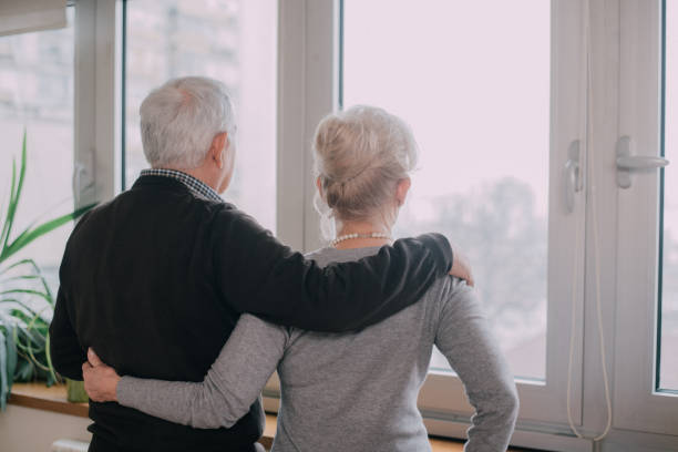 istock Beautiful senior couple looking through the window in their living room 898395708