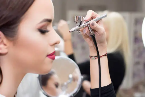 Photo of Makeup artist using airbrusher.