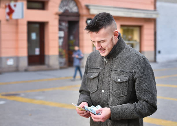 istock young man count money on street 898405364