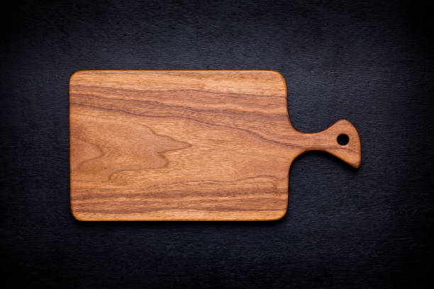 istock Walnut handmade wood cutting board on black wooden board 898406648