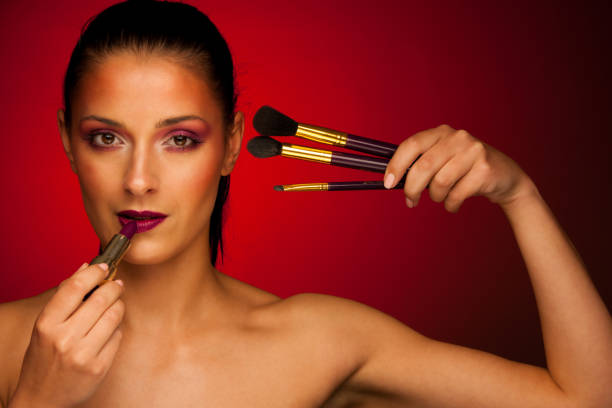 Beautiful young woman with makeeup brushes over dark background