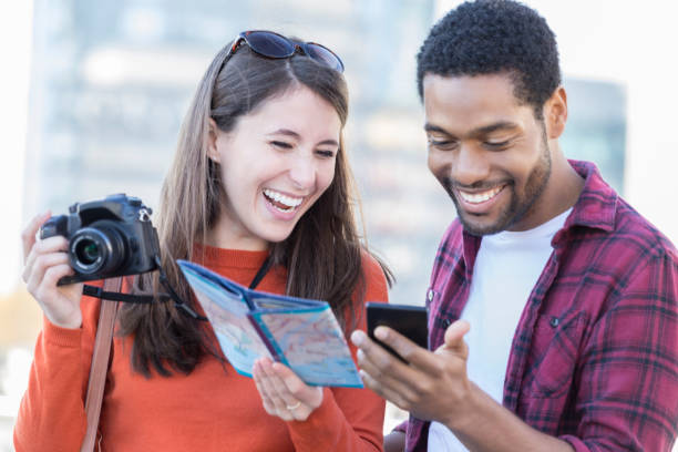 istock Young couple laughs at text while on a city vacation 898424664