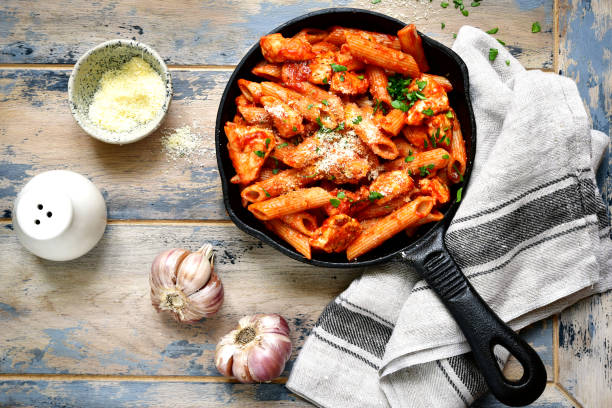 Whole grain pasta with chicken fillet in tomato sauce Whole grain pasta with chicken fillet in tomato sauce in a skillet over old rustic wooden background .Top view. skillet cooking pan photos stock pictures, royalty-free photos & images