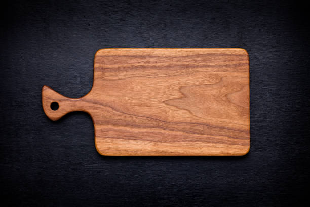 istock Walnut handmade wood cutting board on black wooden board 898429314