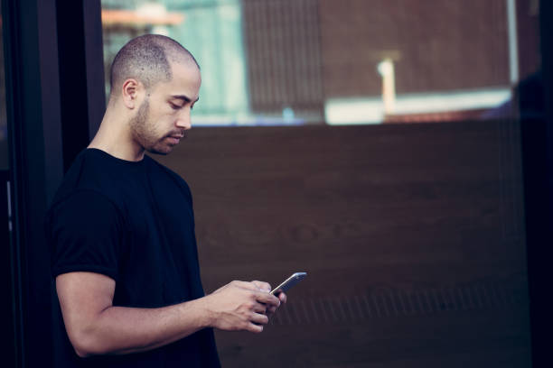 A Maori man using his mobile phone outdoors with copy space. stock photo