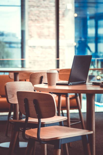 istock Close up image of unoccupied seats in an office environment with laptop computer and coffee cups with no people. 898431924