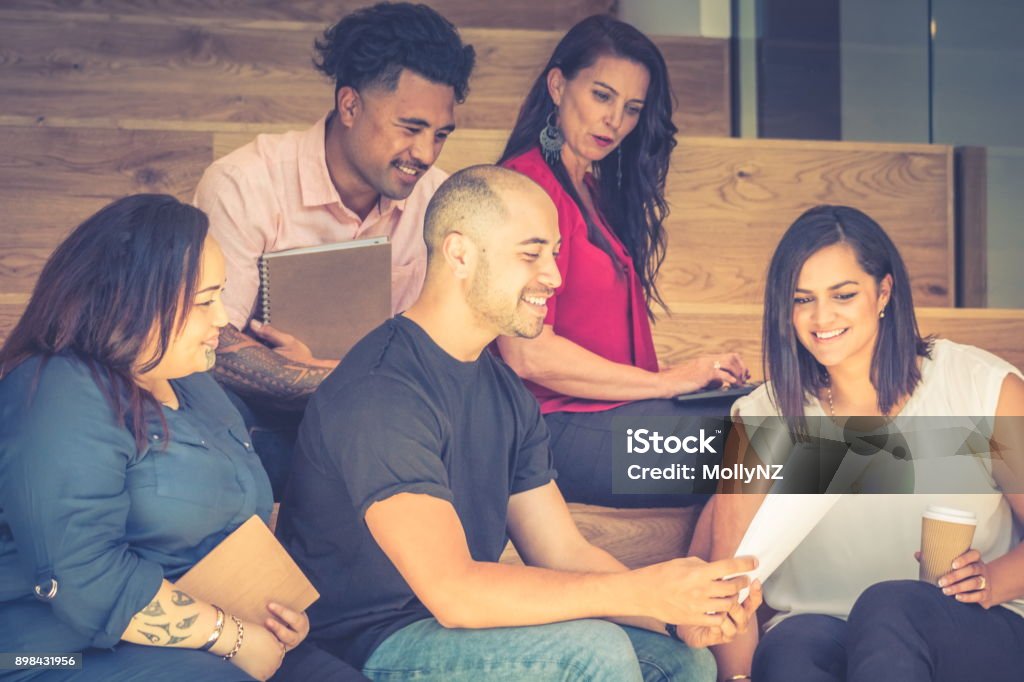 Five business people having a meeting on the stairs in the work environment. Close up image of five business people having a meeting on the stairs in the work environment. New Zealand Stock Photo