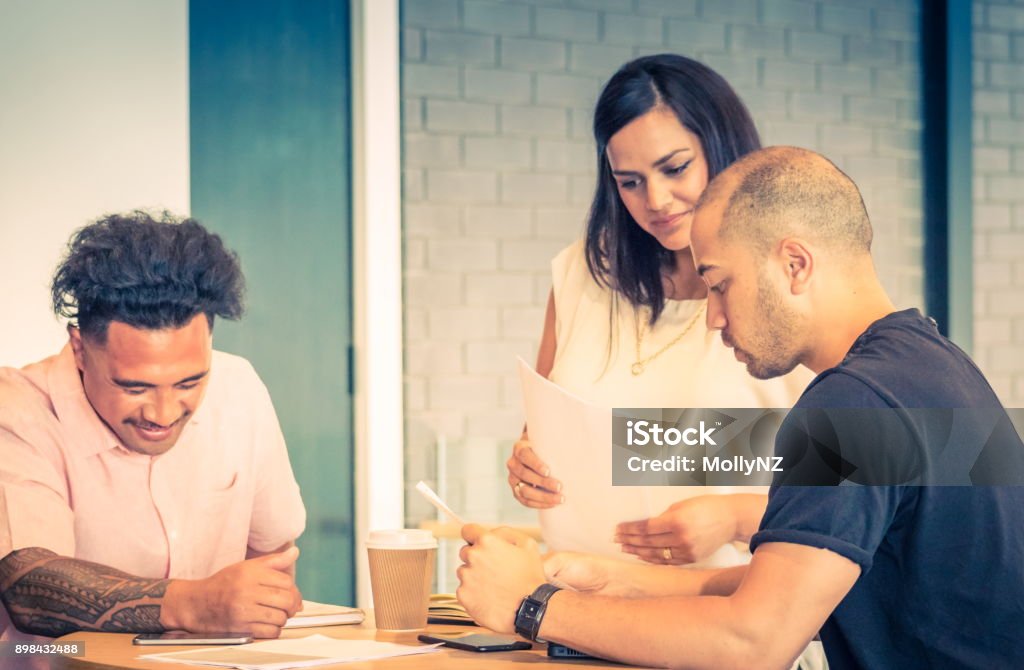 Three New Zealand business people during a work meeting in an office environment. Close up image of three New Zealand business people during a work meeting in an office environment. Māori People Stock Photo