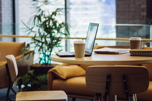 istock Close up image of unoccupied seats in an office environment with laptop computer and coffee cups with no people. 898432694