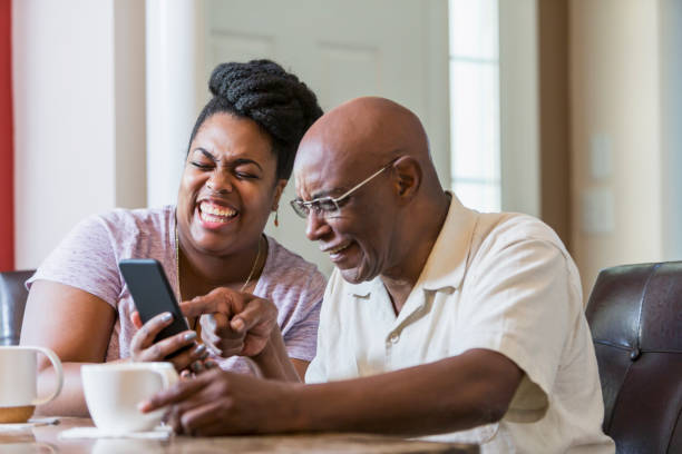 ältere mann mit erwachsenen tochter mit smartphone - women telephone senior adult on the phone stock-fotos und bilder