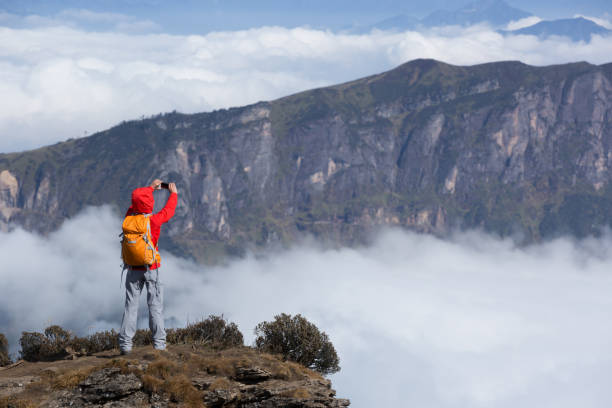istock Successful woman backpacker taking selfie on mountain peak cliff edge 898441130