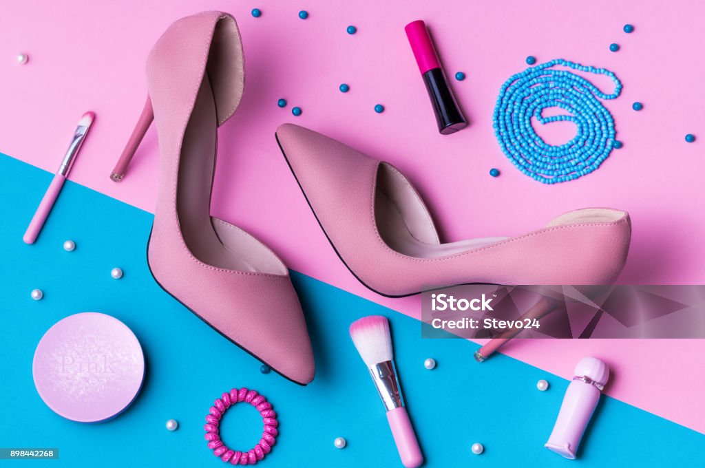 Pink Suede High Heels on pink and blue split background with accessories. Fashion Stock Photo