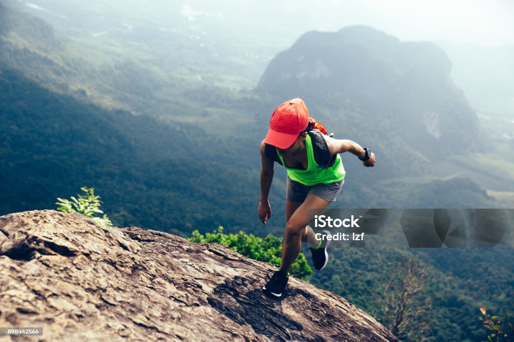 Young fitness woman running up to the mountain top Athlete Stock Photo