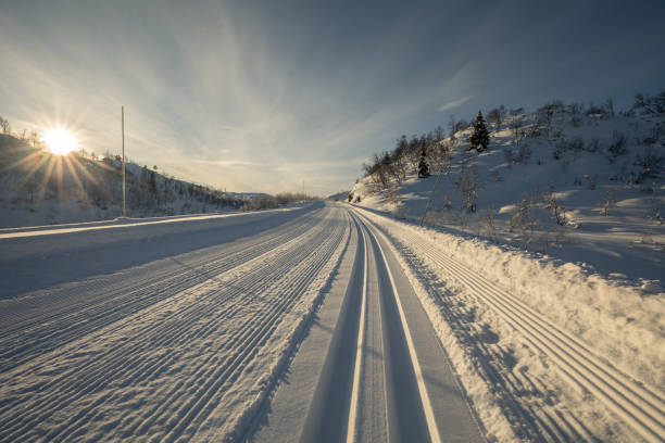 die tiefstehende sonne strahlt auf die frisch präparierten pisten in den bergen im setesdal, norwegen - ski trace stock-fotos und bilder