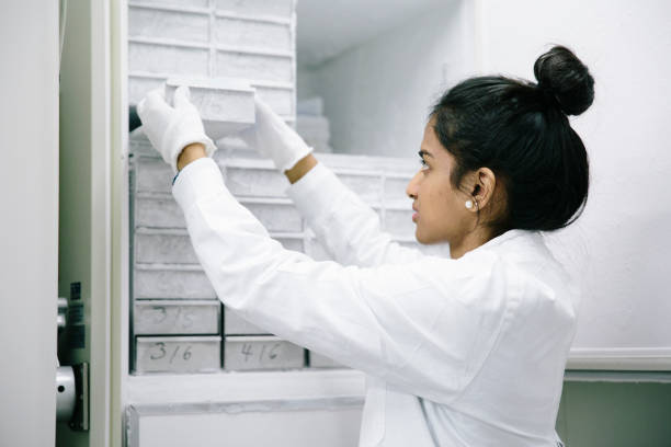 Young woman standing in front of a freezer from laboratory