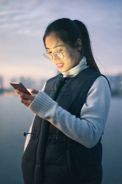 istock woman standing by riverside using phone 898463634
