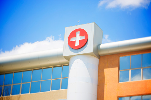 A white on red Red cross symbol on a modern hospital building exterior
