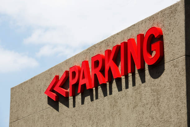 Red parking sign on building expterior with arrows pointing drivers in the right direction