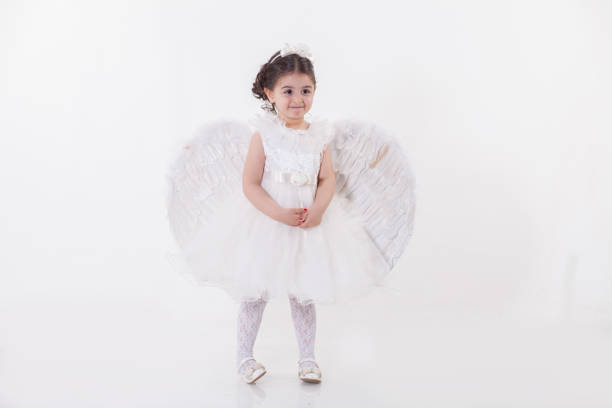 Black and white picture of a little girl dressed as an angel. Smiling with closed eyes.
