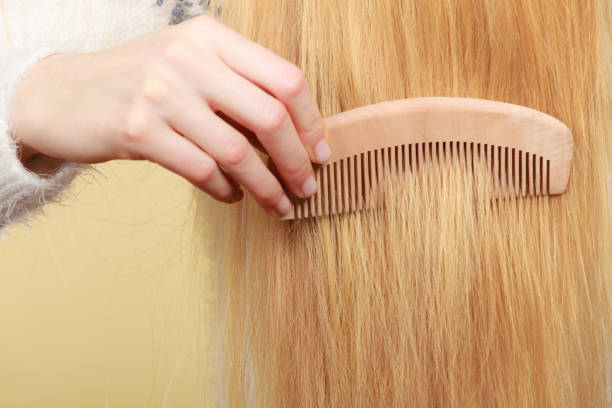 istock Blonde woman brushing her hair with comb 898520154