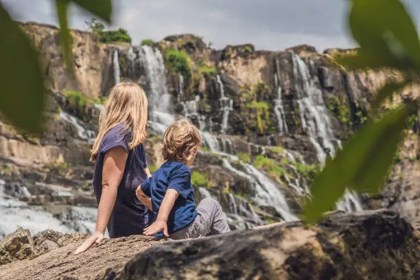 Mother and son hikers, tourists on the background of Amazing Pongour Waterfall is famous and most beautiful of fall in Vietnam. Not far from Dalat city estimate 45 Km. Dalat, Vietnam.