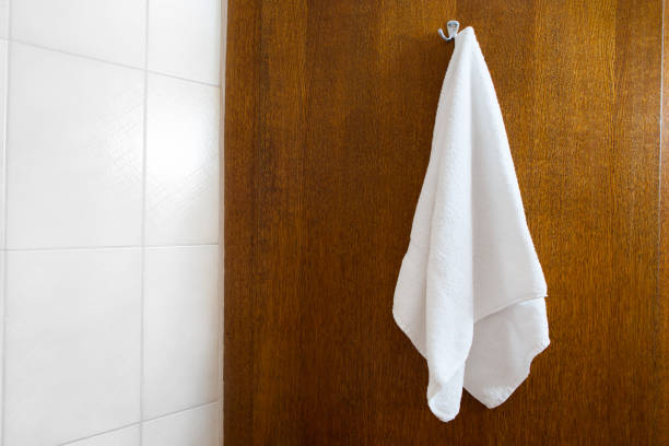 towel hanging on the hook against brown wood background, close-up view